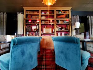 Zwei blaue Sessel in einem Wohnzimmer mit einem Bücherregal in der Unterkunft Hôtel Le Mercator in Vendôme
