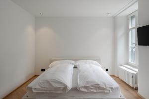 a white bed with white sheets and pillows at ODA Suites - self check-in apartments, old town in Lucerne +19 photos
