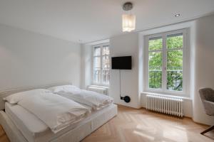 a white bedroom with a bed and a tv at ODA Suites - self check-in apartments, old town in Lucerne