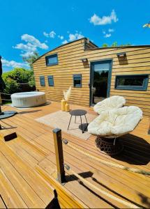 a wooden deck with a tub and a building at Tiny House avec jacuzzi privé - calme et nature in Grabels