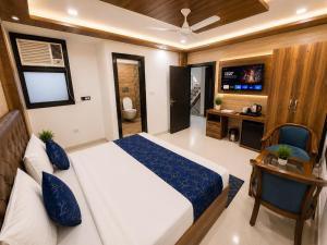 a bedroom with a bed and a desk and a television at Urben BellaMount Hotel - Free Airport and Aerocity Pick Up & Drop in New Delhi