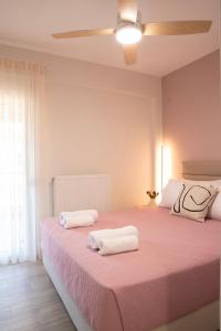 a bedroom with a pink bed with two towels on it at Boheme Apartment in Leptokarya