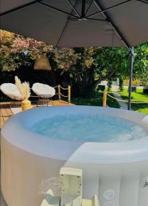 a hot tub in a backyard with an umbrella at Tiny House avec jacuzzi privé - calme et nature in Grabels +7 photos