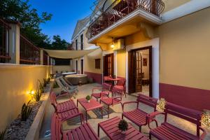 a patio with red chairs and a table at Pinotsi Rooms Village Symi in Symi