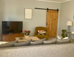 a living room with a couch and a table and a television at The Kite Manor in Langebaan