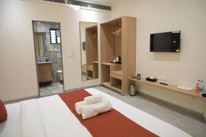 a hotel room with a bed with a tv on the wall at The Bhavani Hotel in Dāhod