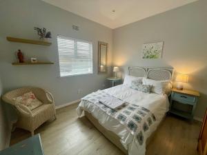 a bedroom with a bed and a chair and a window at The Kite Manor in Langebaan +17 photos