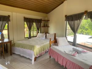 two beds in a room with two windows at Hotel Restaurante Los Cocos in Santa Cruz