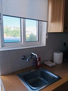 a sink in a kitchen with two windows at STYILEL apartment MIlos 2 in Triovasálos +87 photos