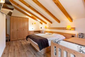 a bedroom with a large bed and wooden floors at Hotel Malga Passerella in Moena