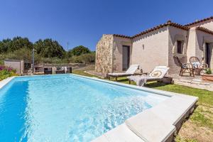 a swimming pool in front of a house at Villa JASMINE SMERALDA in Cala Bitta