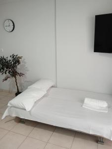 a white bed with pillows and a clock on a wall at Central 26 apartment in Kalamata in Kalamata