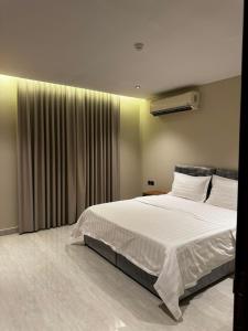 a bedroom with a large white bed and a window at الشهداء الفاخر للشقق المخدومة in Medina +10 photos