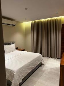 a bedroom with a large white bed and curtains at الشهداء الفاخر للشقق المخدومة in Medina