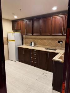a kitchen with wooden cabinets and a white refrigerator at الشهداء الفاخر للشقق المخدومة in Medina