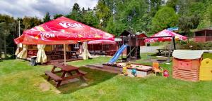 a play area with a coke umbrella and a playground at Chata na kolech 4L v areálu Koupaliště Bystré v Orlických horách in Bystré