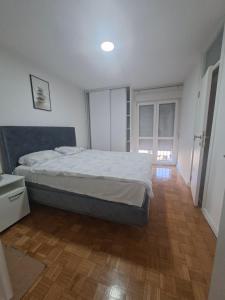 a bedroom with a bed and a wooden floor at Apartman Mirjana 2 spavace odvojene sobe in Banja Luka