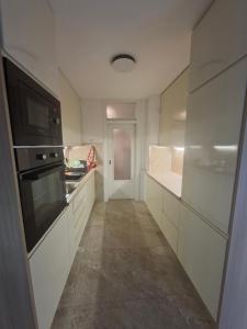 a kitchen with white cabinets and a black appliance at Apartman Mirjana 2 spavace odvojene sobe in Banja Luka