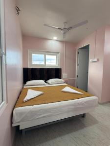 a large bed in a pink room with two pillows at Chandralok Service Apartments in Kolhapur