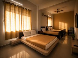 ein Schlafzimmer mit zwei Betten und einem Fenster in der Unterkunft Naadi stayinn -Premium Rooms in Thanjavur