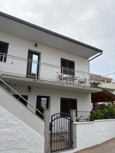 a white house with a balcony with chairs on it at Apartman Velina in Pakoštane
