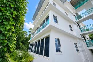 a white building with balconies and trees at High Five Hotels Phase 2 in Assagao