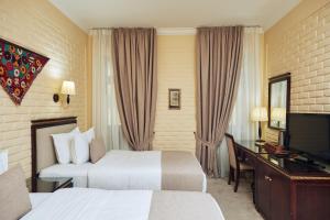 a hotel room with two beds and a desk and a television at Hotel Grand Samarkand Superior - A in Samarkand