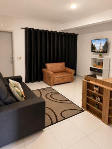 a living room with a couch and a chair at LEON MARIA HOSPEDAGENS - Smart Flat Hotel e Residence in Mogi das Cruzes