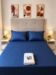 a bed with a blue comforter and a towel on it at LEON MARIA HOSPEDAGENS - Smart Flat Hotel e Residence in Mogi das Cruzes