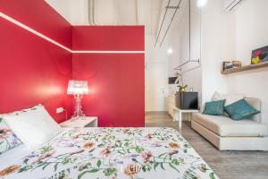 a bedroom with a red wall and a bed and a couch at Wine Passion Room in Quartu SantʼElena