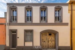 a building with four windows and two doors at Wine Passion Room in Quartu SantʼElena