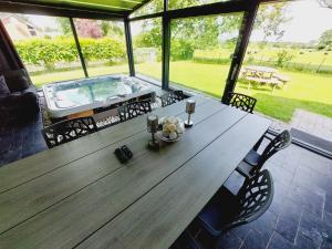 a large wooden table with chairs next to a hot tub at Villa VIP in Welkenraedt