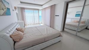 a white bedroom with a large mirror and a bed at Le paradis 210 in Kelibia