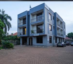 a blue building with cars parked in a parking lot at Esther properties in Entebbe