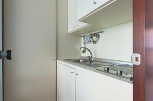 a kitchen with white cabinets and a sink at Youhosty - Duomo Studio Apartment in Milan +26 photos