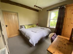 a bedroom with a bed and a window and a table at The Hideaway Embleton in Embleton