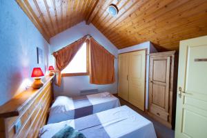 a bedroom with two beds and a wooden ceiling at LesChalets de Pré Genty in Oz
