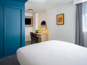 a room with a bed and a desk with a blue door at Garner Hotel Wolverhampton by IHG in Wolverhampton +43 photos