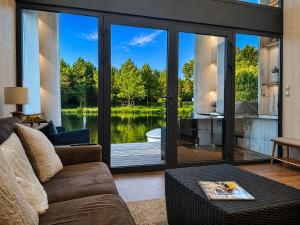 a living room with sliding glass doors that look out onto a lake at Les Kabanes de Kerforn in Crach