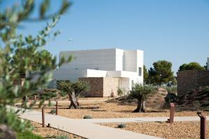 a building in the desert with trees in the foreground at Luz de Alba in Argamasilla de Alba
