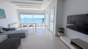 a living room with a couch and a television and the ocean at Le paradis 210 in Kelibia