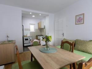 a kitchen and living room with a wooden table with flowers at Apartman Mila Raška in Raška
