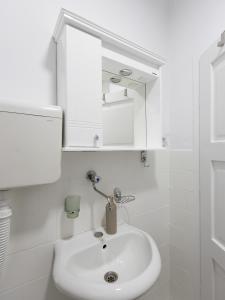 a white bathroom with a sink and a mirror at Apartman Mila Raška in Raška