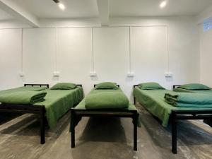 two beds with green pillows in a room at Goshen dormitory in Siliguri