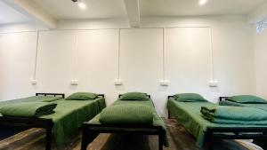 two beds in a room with green sheets at Goshen dormitory in Siliguri