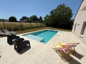 a swimming pool with two chairs and a table and chairs at Villa à Lux in Lux