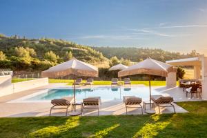 a pool with chairs and umbrellas and a table at Kallies villas with shared Pool in Pefkochori