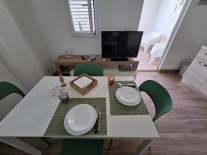 a dining room table with green chairs and a television at AM-MARE in Villaggio Azzurro
