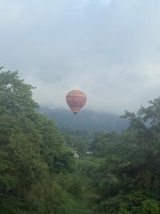 a hot air balloon flying in the sky over trees at The Big Brother Mouse Hostel in Vang Vieng