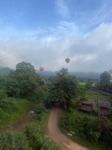 two hot air balloons flying over a dirt road at The Big Brother Mouse Hostel in Vang Vieng